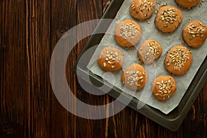 Fresh homemade crispy bread buns with bran, sunflower and pumpkin seeds on baking sheet. Top view