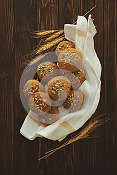 Fresh homemade crispy bread buns with bran, sunflower and pumpkin seeds on brown wooden background. Top view