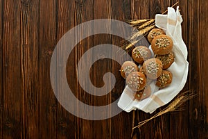 Fresh homemade crispy bread buns with bran, sunflower and pumpkin seeds on brown wooden background. Top view