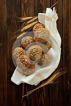 Fresh homemade crispy bread buns with bran, sunflower and pumpkin seeds on brown wooden background. Top view