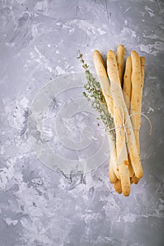 Fresh homemade crispy bread sticks with thyme and sea salt on a gray concrete background herbs