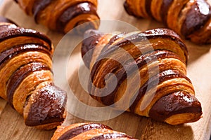 Fresh homemade croissants with chocolate on wood surface