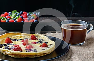 Fresh homemade dutch baby pancake with blueberry raspberry and strawberry on a plate on a table.