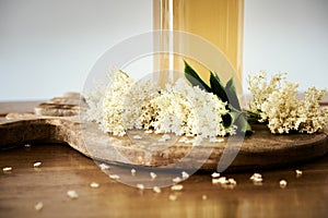 Fresh homemade elderflower cordial closeup with small white flowers and a bottle detail with the sweet drink. Sugary spring aroma