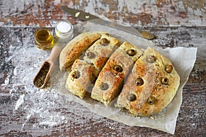 Fresh homemade focaccia with italian herbs. Cooking at home. Traditional italian bread with olives.