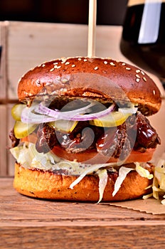 Fresh homemade hamburger with beef, onion, sause and cabbage garnish on a wooden board, wooden table background. Juicey