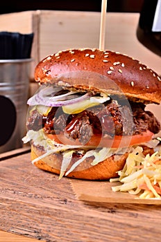 Fresh homemade hamburger with beef, onion, sause and cabbage garnish on a wooden board, wooden table background. Juicey