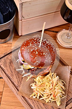 Fresh homemade hamburger with beef, onion, sause and cabbage garnish on a wooden board, wooden table background. Juicey