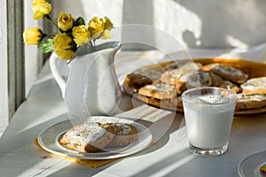 Fresh homemade lemon poppyseed cookies on a table next to a bright window.