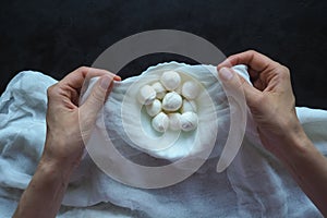 Fresh homemade mozzarella cheese in cheesecloth on the black background. Top view. photo