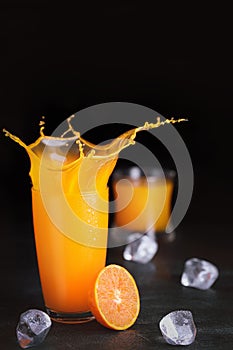 Fresh homemade orange juice in glass with ice on vintage wooden table. Freshness beverage with splash and fruit for healthy and di