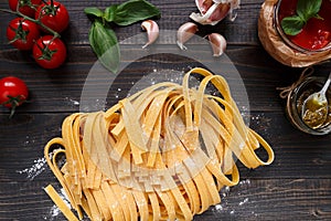 Fresh homemade pasta and vegetables on the dark wooden table top view