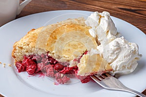 Fresh homemade pie with cherry pulp and ice cream on a plate. A slice of a cherry pie with a ruddy crust on a wooden table.