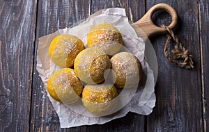 Fresh homemade pumpkin buns yeast-free with cardamom sprinkled with icing sugar on wooden board