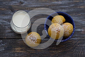 Fresh homemade pumpkin cardamom buns yeast-free with milk sprinkled with icing sugar on wooden board