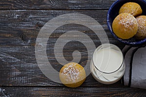 Fresh homemade pumpkin cardamom buns yeast-free with milk sprinkled with icing sugar on wooden board