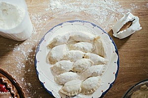 Fresh homemade ravioli, dumplings or pelmeni covered in flour on a wooden table. Raw, uncooked.