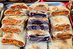 Fresh homemade sour cherries and pumpkin pie pieces displayed for sale at a street food market, side view of healthy food photogra