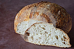 Fresh homemade sourdough bread with whole grain flour on a on a brown background.