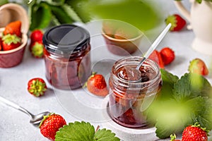 Fresh homemade strawberry jam in glass jar on a light background