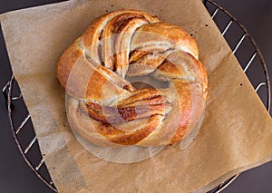 Fresh homemade sweet yeast bread swirl bun with cinnamon. On paper for baking. Selective focus.