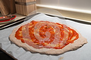 Fresh homemade tomato sauce overlaying a fresh italian pizza dough