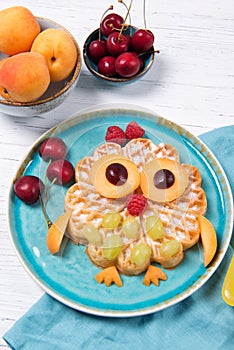 Fresh homemade waffle with fruits and berries in the shape of cute owl with balloons, food for kids idea