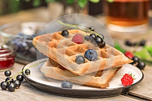 Fresh homemade waffles with blackberries, Jam, tea, leaves, berries