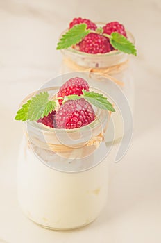 Fresh homemade yogurt decorated with fresh raspberry and mint/Two glass jars with fresh homemade yogurt decorated with fresh