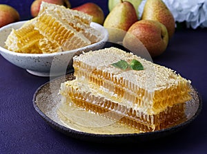 Fresh honey in honeycomb, pears on purple background. Folk method of treating colds. Side view, selective focus