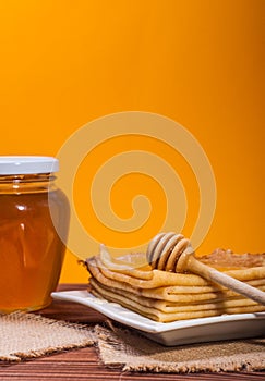 Fresh honey with a Stack of blinis or crepes