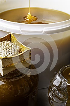 fresh honey in white bucket and in glass jar, with honeycomb