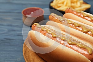 Fresh hot dogs with mustard on wooden table