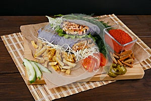 Fresh hot fragrant shawarma cut lies on a wooden board with vegetables, green leaves and fries