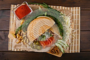 Fresh hot fragrant shawarma cut lies on a wooden board with vegetables, green leaves and fries