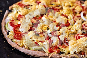 Fresh hot homemade veggie pizza with cutting vegetables - tomatoes, bell pepper, onion, cheese close up on a dark background