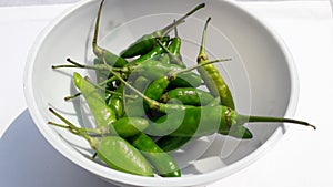 Fresh hot spicy green chili or cabe rawit hijau on bowl on white background