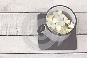 Fresh hot tea with jasmine flowers in white metal cup