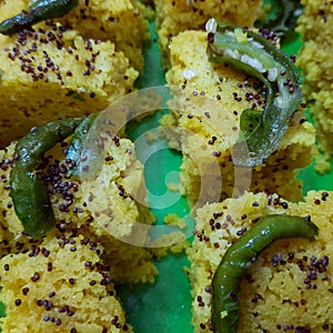 Fresh and hot yellowish khaman dhokla with spices made at home, India, Yummy and delicious home made khaman dhokla with hot green