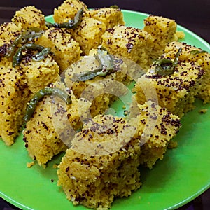 Fresh and hot yellowish khaman dhokla with spices made at home, India, Yummy and delicious home made khaman dhokla with hot green