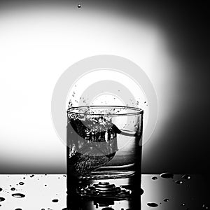 Fresh ice cube falling to glass of water splash isolated