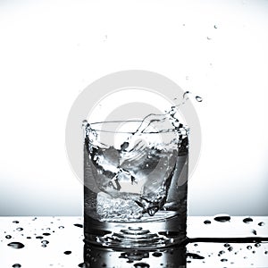 Fresh ice cube falling to glass of water splash isolated