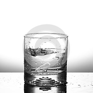 Fresh ice cube falling to glass of water splash isolated