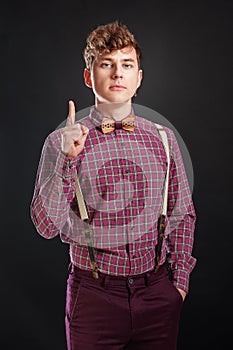 Fresh idea! Attention! Handsome young man in vintage shirt and curly hair keeping finger raised and looking at camera