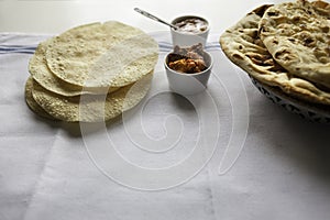 Fresh Indian flat breads Naans and poppadums served on the white cloth