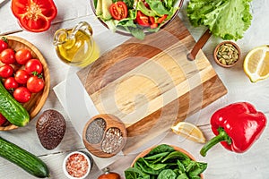 Fresh ingredients for cooking salad and empty wooden cutting board . Healthy clean eating, vegetarian food and diet