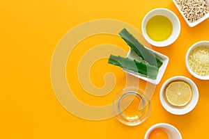 Fresh ingredients for homemade effective acne remedies on yellow background. Honey, sea salt, egg yolk, olive oil, oat, lemon and