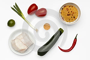 Fresh ingredients to make cajun hake, with vegetables and couscous on a bright white background