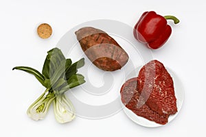 Fresh ingredients to make cajun rump beef, with vegetables and spices on a white background