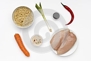 Fresh ingredients to make chicken chow mein, with vegetables and noodles on a bright white background